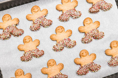 Three diagonal rows of gingerbread men on baking paper in a baking dish