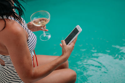 Midsection of man using mobile phone in swimming pool