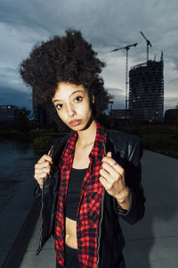 Young woman wearing leather jacket in city at dusk