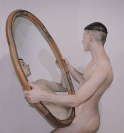 Side view of a young man playing piano against white background