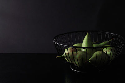 Close-up of green fruit on table against black background