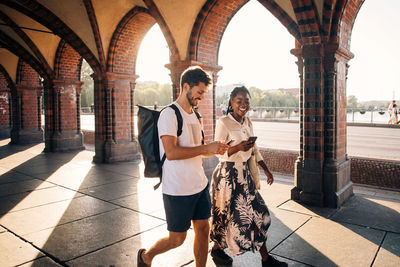 Young male and female friends walking on footpath in city