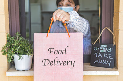 Woman standing by potted plant with text