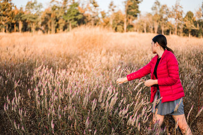 Side view of young woman standing on field