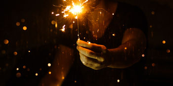 Midsection of man holding sparkler at night