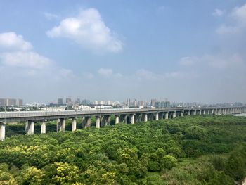 Bridge over river in city against sky