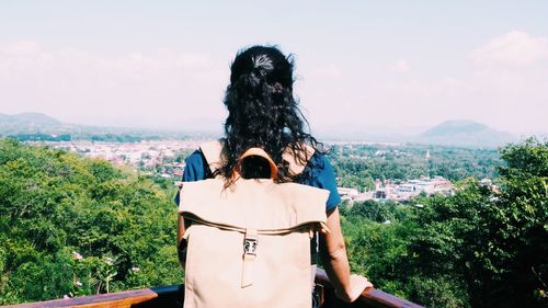 Rear view of woman carrying backpack while looking at cityscape