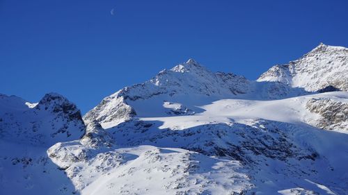 Scenic view of snowcapped mountains against clear blue sky