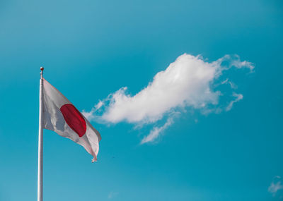 Low angle view of japanese flag waving against blue sky