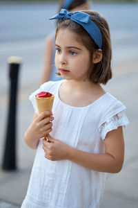 Cute girl holding ice cream cone while standing outdoors