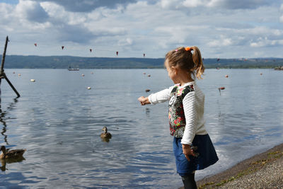 Side view of girl standing at lakeshore