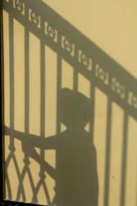 Shadow of man standing on railing against wall