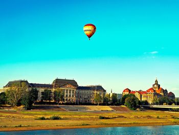 Hot air balloon flying over buildings against clear sky