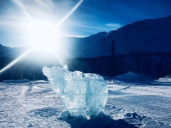 Scenic view of snow covered mountains against bright sun