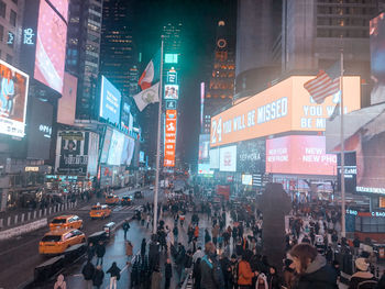 Crowd on city street amidst buildings at night