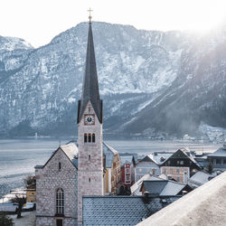 Church by buildings against mountains during winter