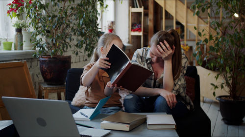 Girl showing book to teacher at home