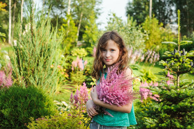 Portrait of girl standing on purple flowering plants