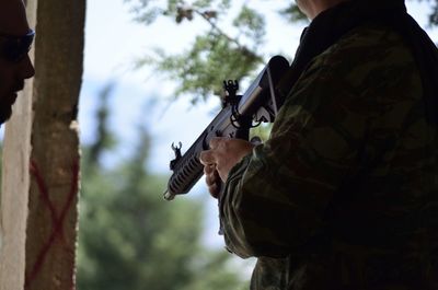 Midsection of man holding gun while standing outdoors