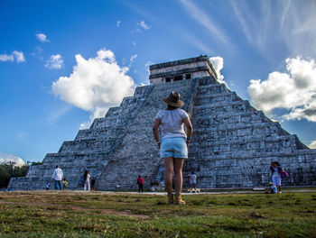 Low angle view of tourists against cloudy sky