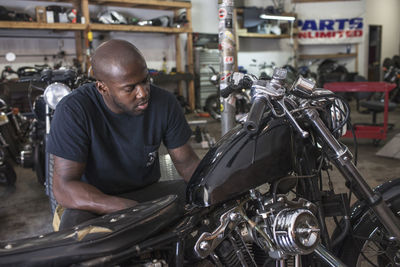 A young man fixing a motorcycle.