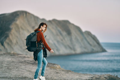 Full length of man on rock at beach against sky