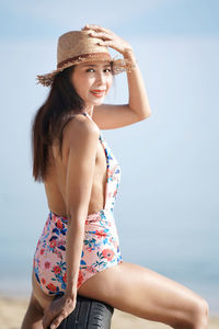 Beautiful young woman wearing hat on beach against sky