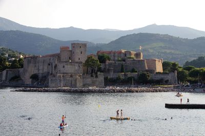 People on mountain by lake against sky