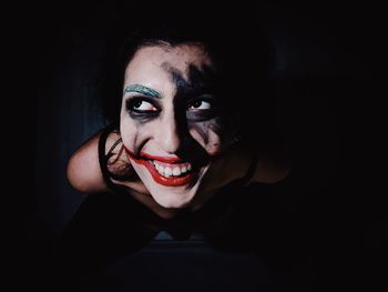 Close-up portrait of young woman with eyes closed against black background