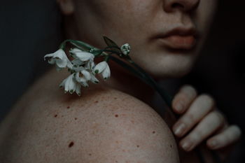 CLOSE-UP OF WOMAN WITH PINK FLOWER IN SUNLIGHT