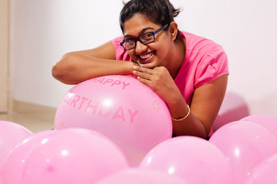 Portrait of a smiling young woman with pink balloons