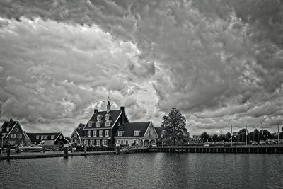 Houses by river and buildings against sky