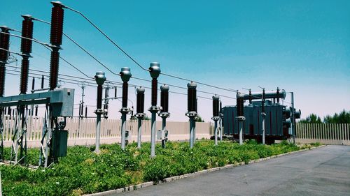 Transformers at substation against clear blue sky