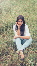 High angle portrait of young woman sitting on grassy field at park