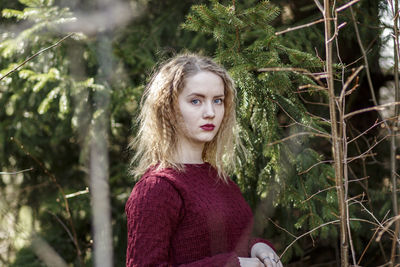 Portrait of young woman standing by tree