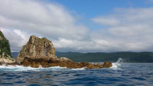 Rock formations on sea shore against sky