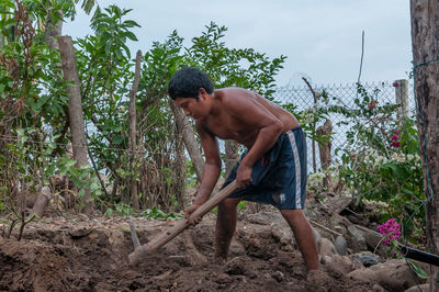 Side view of shirtless young man lying on land