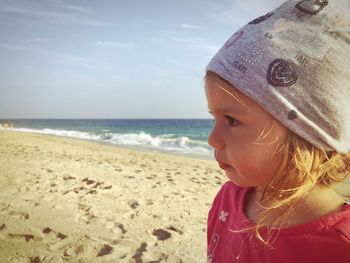 Side view of girl wearing knit hat at beach