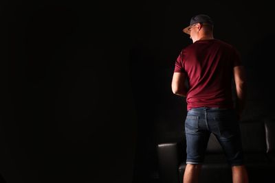 Rear view of man standing against black background