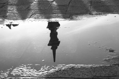 Reflection of woman on puddle in lake