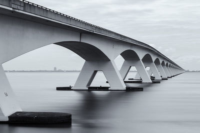 Bridge over calm river against sky