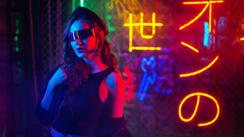 Portrait of young woman standing against graffiti