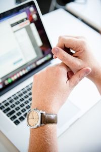 Close-up of man using laptop on table