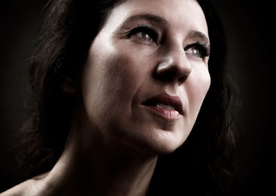 Close-up of thoughtful woman over black background