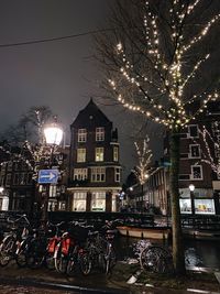 Bicycles parked on street by buildings at night