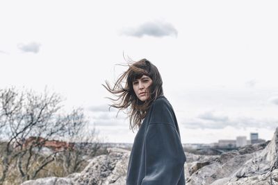 Portrait of smiling woman standing against sky