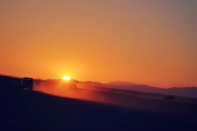 Scenic view of silhouette landscape against orange sky