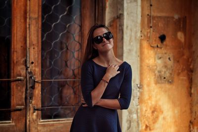 Portrait of smiling beautiful woman standing against old house