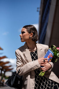 Side view of women using magazine and bouquet 