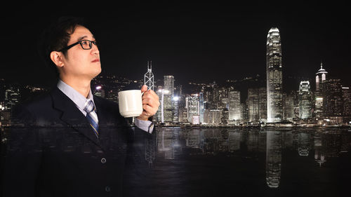 Man and illuminated buildings against sky at night